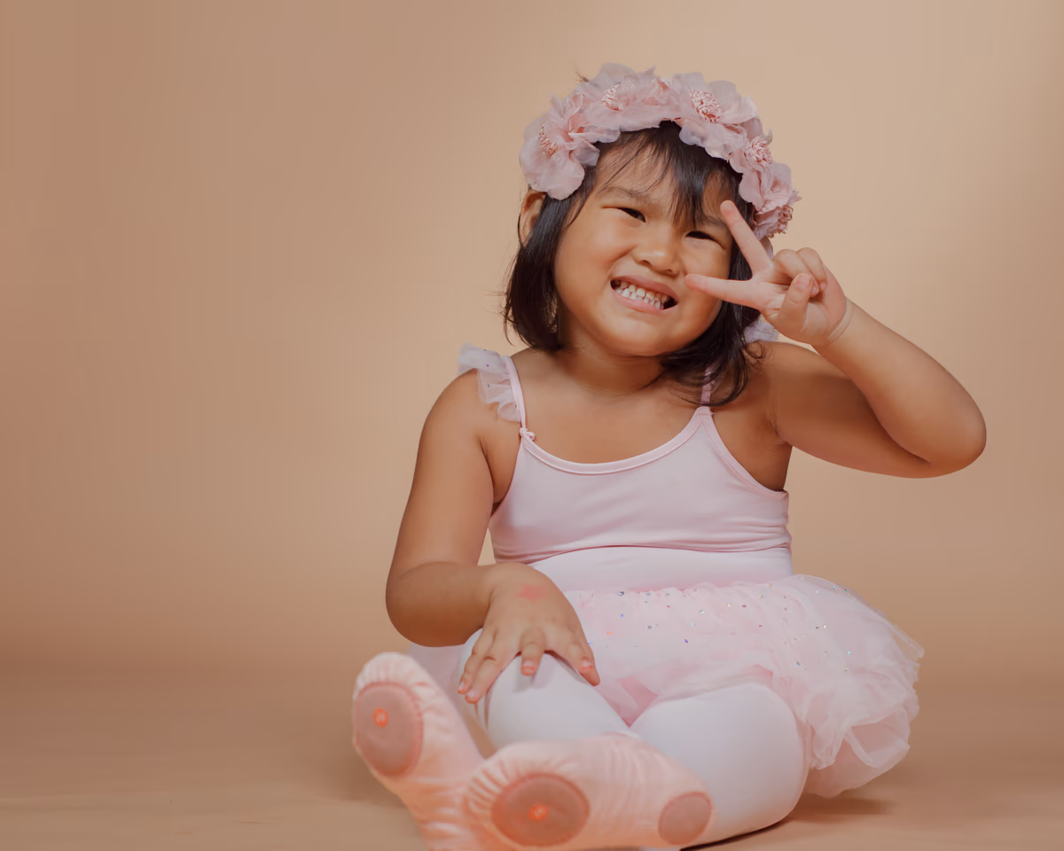 Smiling ballerina with a peace sign in soft studio light