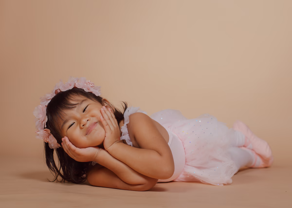 Playful ballerina resting on her elbows in the studio