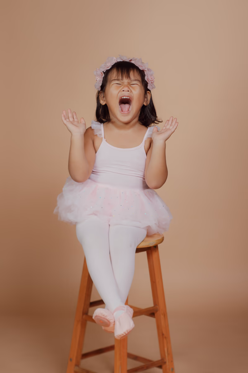 Joyful ballerina cheering on a studio stool