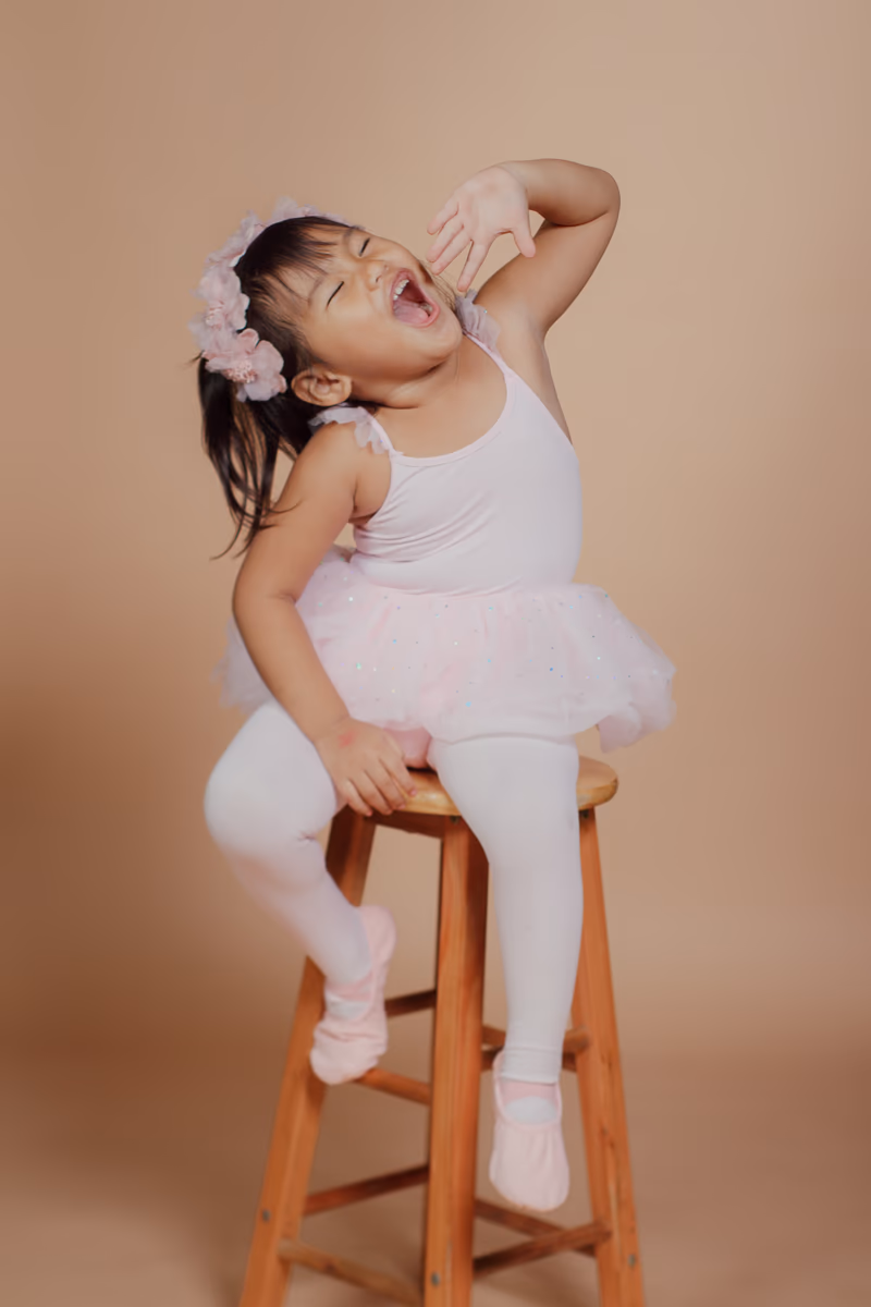 Laughing ballerina seated on a wooden stool