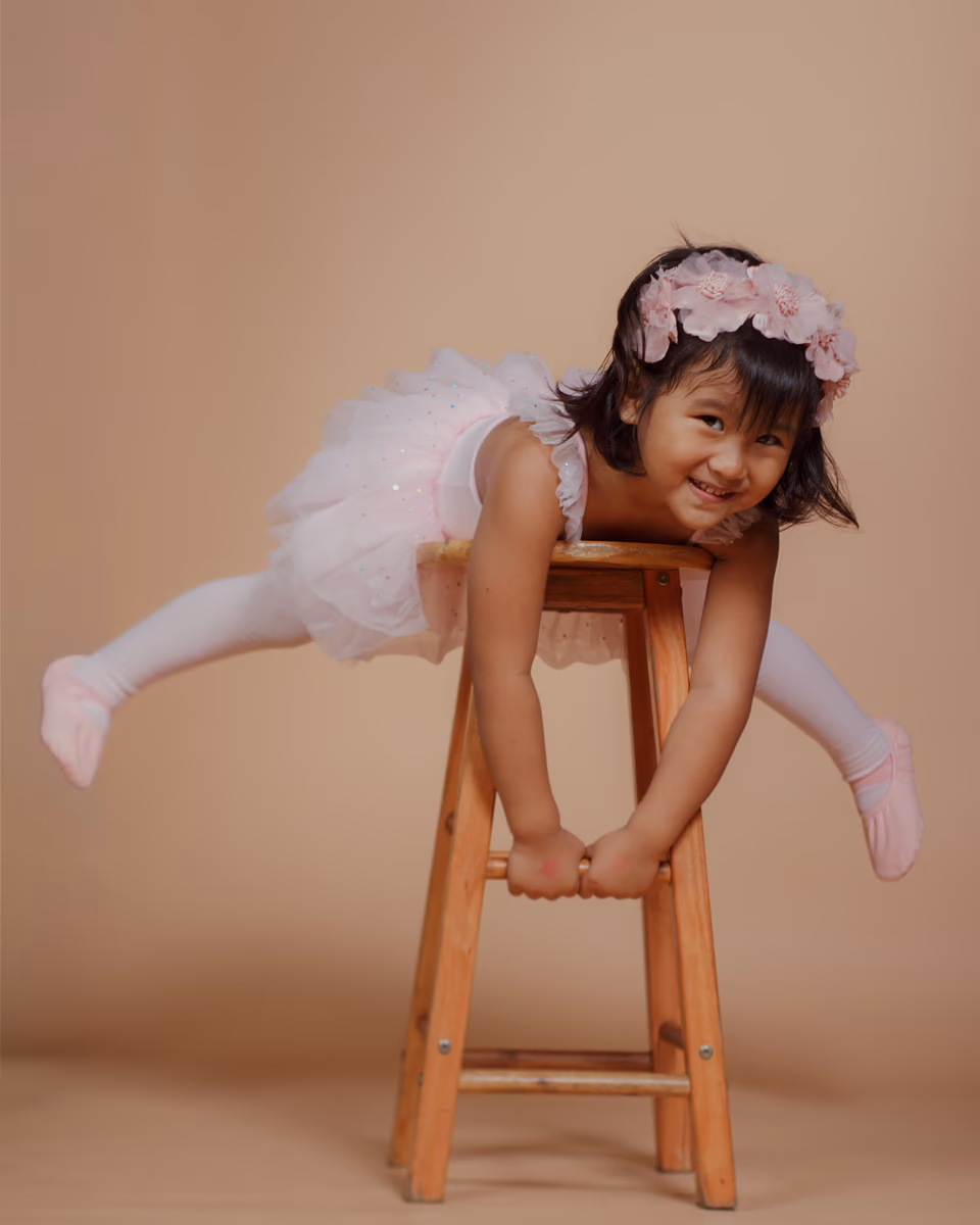 Young ballerina playfully balancing on a wooden stool