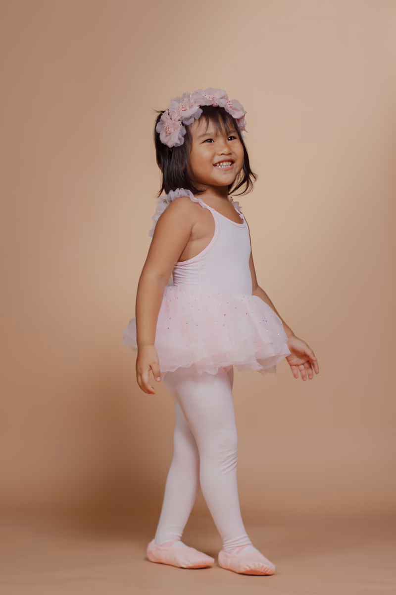Ballerina in pink tutu standing in profile
